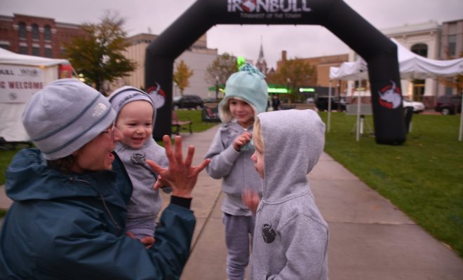 Executive director Andrea Larson gives three children high fives at the finish line of the inaugural IRONBULL Red Granite Grinder bike race.
